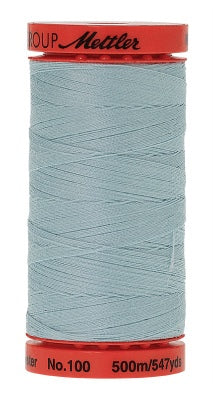 A spool of light blue sewing thread with red plastic end caps. The top cap is red with the brand 'Mettler' printed in black, and the bottom cap is red with text indicating 'No.