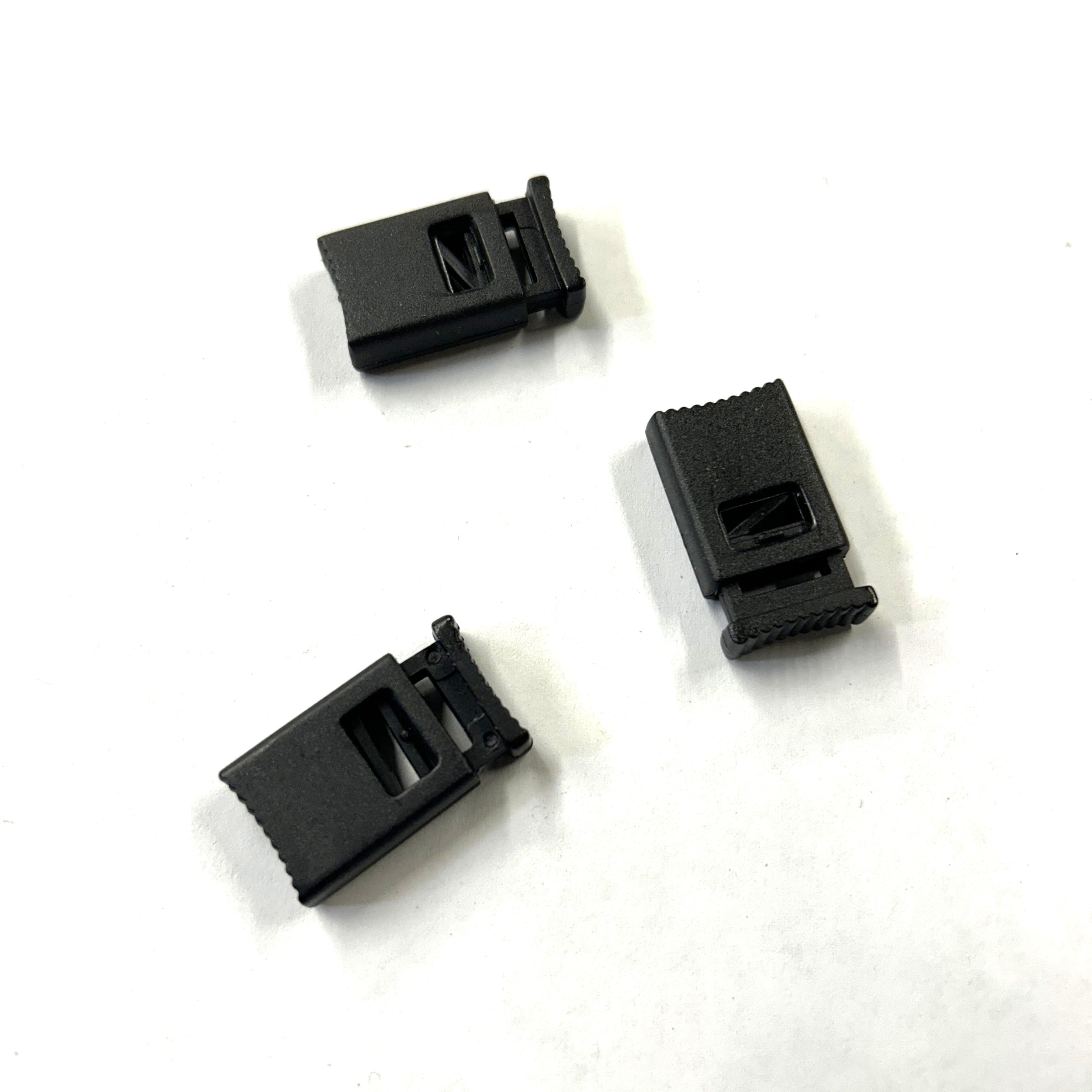 Three black plastic toggles on a white background